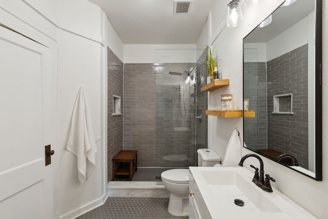 bathroom with toilet, tile patterned floors, tiled shower, and vanity