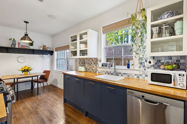 kitchen with pendant lighting, sink, white cabinetry, stainless steel appliances, and butcher block counters