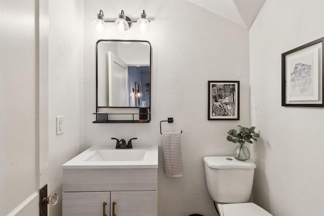 bathroom featuring toilet, vaulted ceiling, and vanity