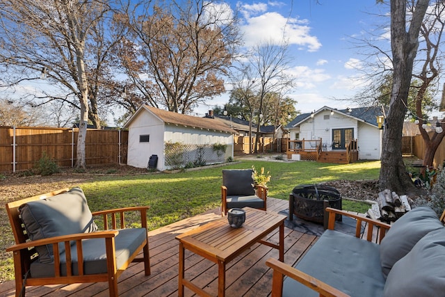 wooden terrace featuring a lawn, a shed, and an outdoor living space