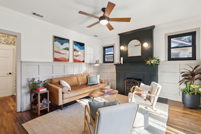 living room featuring ceiling fan, ornamental molding, a fireplace, and hardwood / wood-style flooring