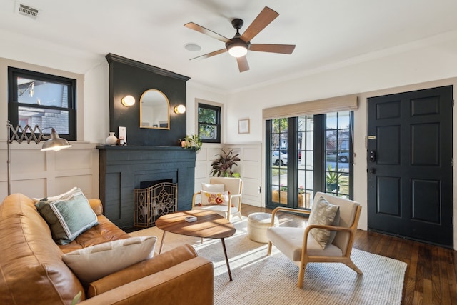 living room featuring a brick fireplace, ornamental molding, dark hardwood / wood-style flooring, and ceiling fan