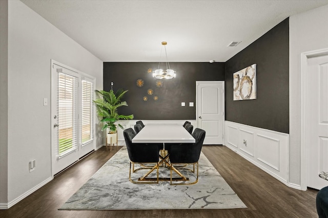 dining space with dark hardwood / wood-style floors and a notable chandelier