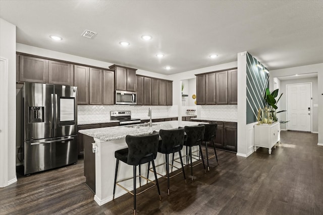 kitchen with sink, dark brown cabinetry, appliances with stainless steel finishes, and a kitchen island with sink