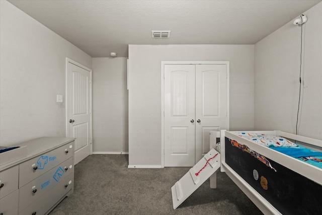 bedroom with dark carpet and a textured ceiling