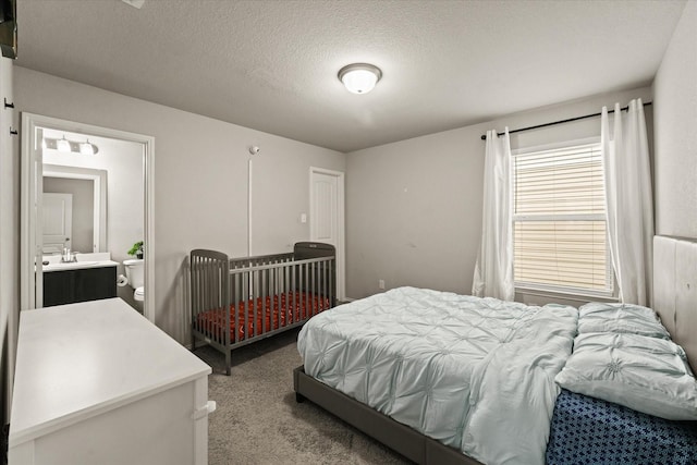 carpeted bedroom featuring connected bathroom and a textured ceiling