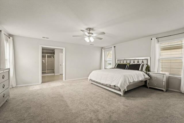 bedroom with ceiling fan, a textured ceiling, carpet floors, and ensuite bath