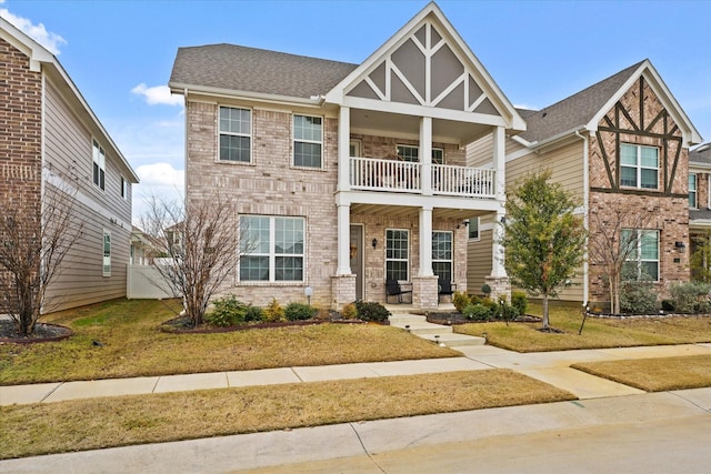 view of front of house featuring a balcony, covered porch, and a front yard