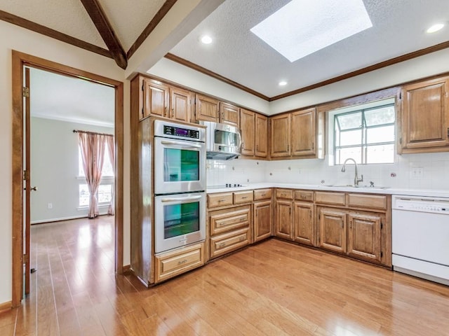 kitchen with decorative backsplash, sink, stainless steel appliances, and light hardwood / wood-style flooring