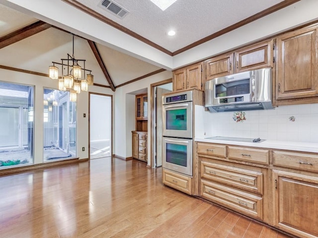 kitchen featuring pendant lighting, stainless steel appliances, decorative backsplash, lofted ceiling with beams, and a chandelier