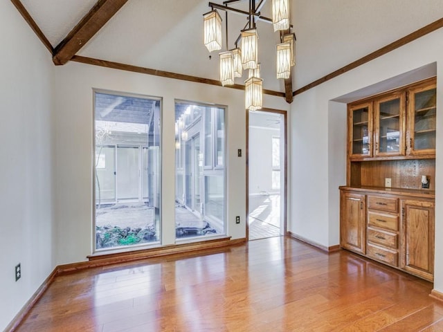 unfurnished dining area featuring lofted ceiling with beams and hardwood / wood-style flooring