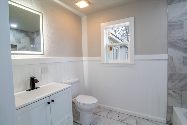 bathroom featuring toilet, vanity, and a tub