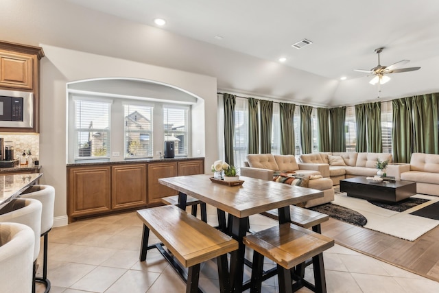 tiled dining room featuring ceiling fan and vaulted ceiling