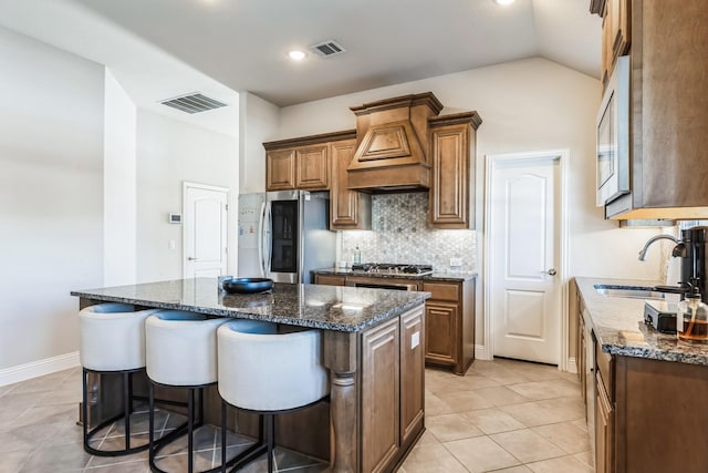 kitchen featuring a kitchen island, sink, appliances with stainless steel finishes, custom range hood, and dark stone counters