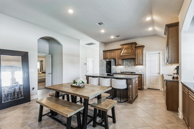 dining space with sink, vaulted ceiling, and light tile patterned flooring