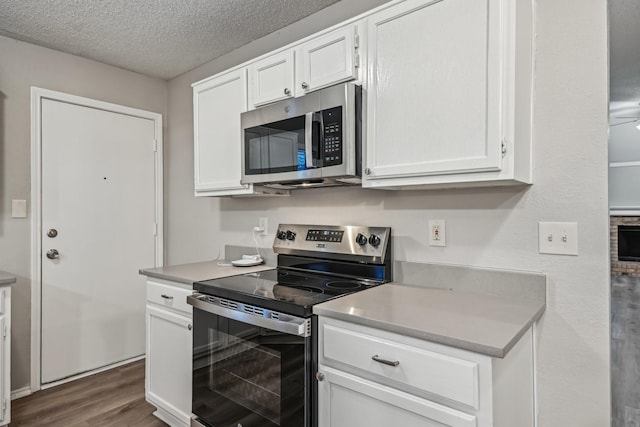 kitchen with a textured ceiling, stainless steel appliances, dark hardwood / wood-style flooring, and white cabinets