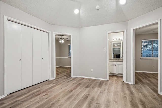 unfurnished bedroom featuring connected bathroom, a textured ceiling, and light hardwood / wood-style floors