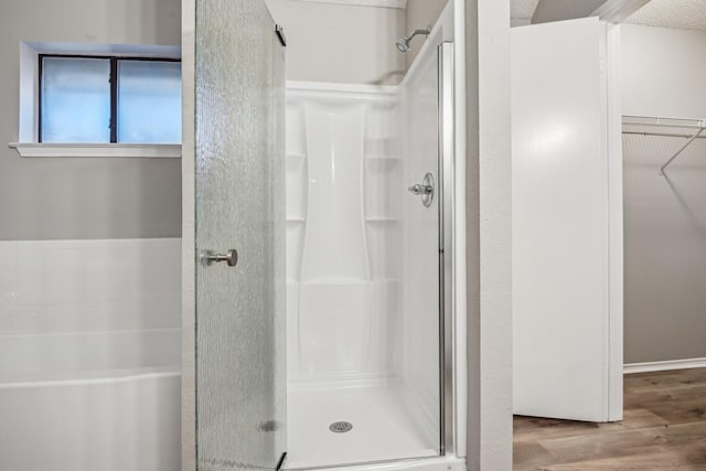 bathroom with a shower with shower door and hardwood / wood-style floors