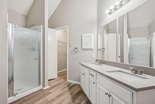 bathroom with lofted ceiling, wood-type flooring, an enclosed shower, a textured ceiling, and vanity