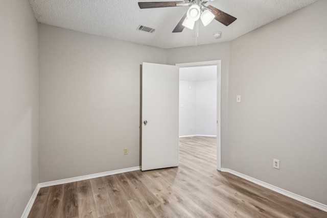 empty room with a textured ceiling and light hardwood / wood-style flooring