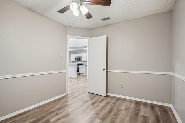 unfurnished room featuring ceiling fan, light wood-type flooring, and a textured ceiling