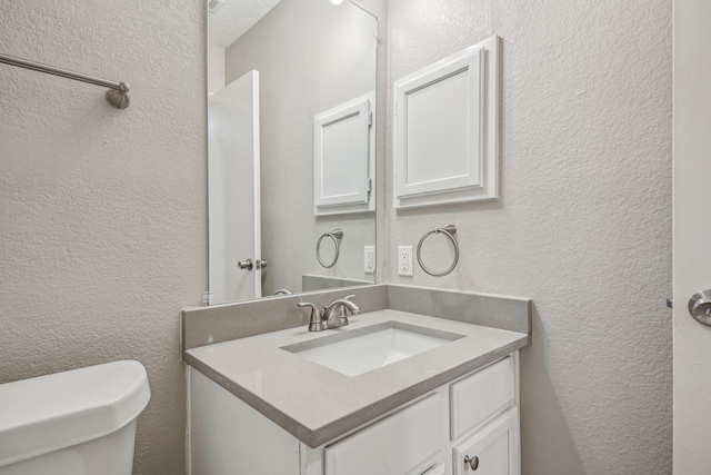 bathroom featuring toilet, vanity, and a textured ceiling