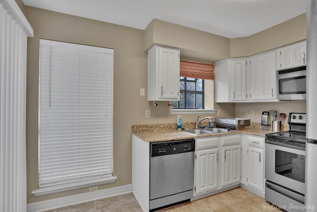 kitchen with light tile patterned floors, appliances with stainless steel finishes, white cabinetry, and sink