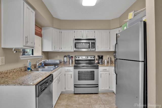 kitchen featuring light tile patterned floors, white cabinetry, stainless steel appliances, a textured ceiling, and sink