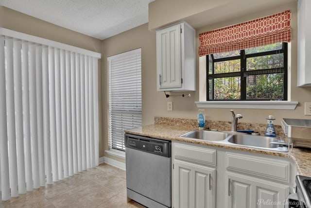 kitchen featuring stainless steel dishwasher, sink, light tile patterned flooring, a textured ceiling, and white cabinets