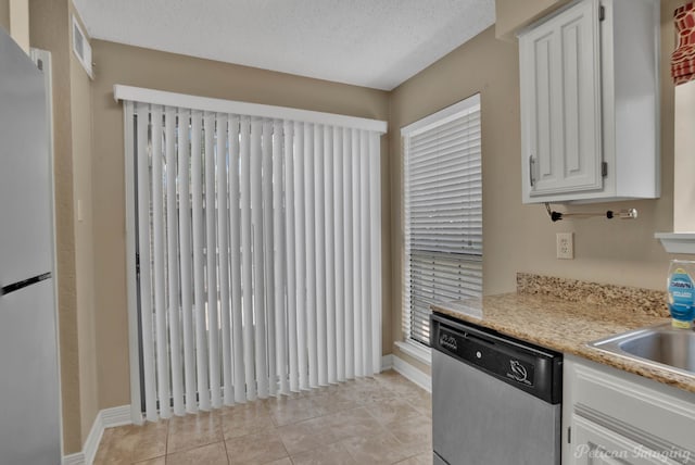 kitchen featuring stainless steel dishwasher, fridge, light tile patterned flooring, a textured ceiling, and white cabinets