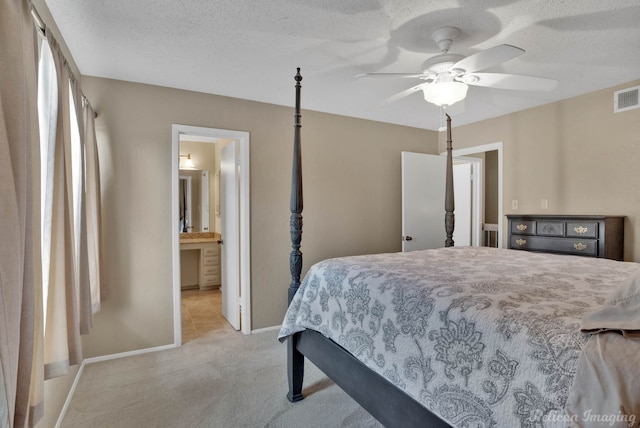 bedroom featuring ceiling fan, connected bathroom, light carpet, and a textured ceiling