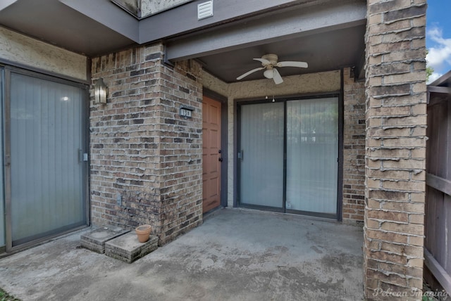 view of exterior entry with ceiling fan and a patio area