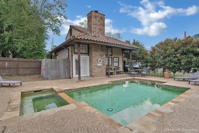 rear view of house featuring a swimming pool with hot tub and a patio