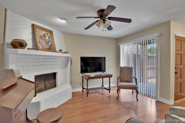 living room featuring a textured ceiling, ceiling fan, a fireplace, and hardwood / wood-style floors