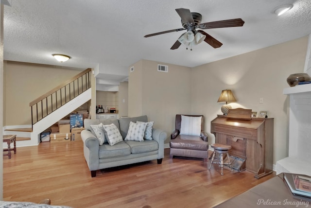 living room featuring ceiling fan, wood-type flooring, and a textured ceiling