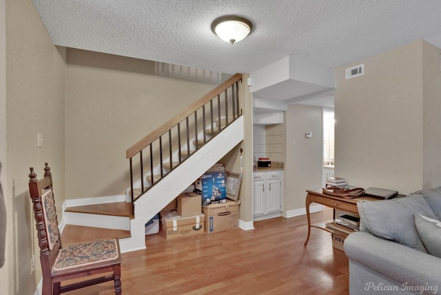 living room featuring a textured ceiling and light hardwood / wood-style flooring