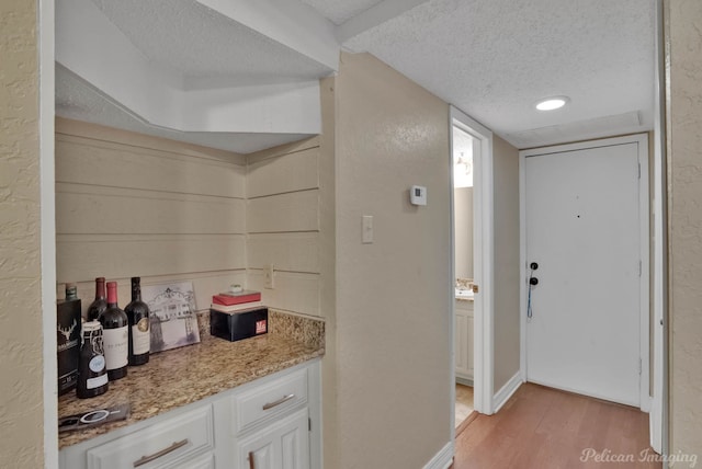 kitchen featuring white cabinets, light stone counters, a textured ceiling, and light hardwood / wood-style floors