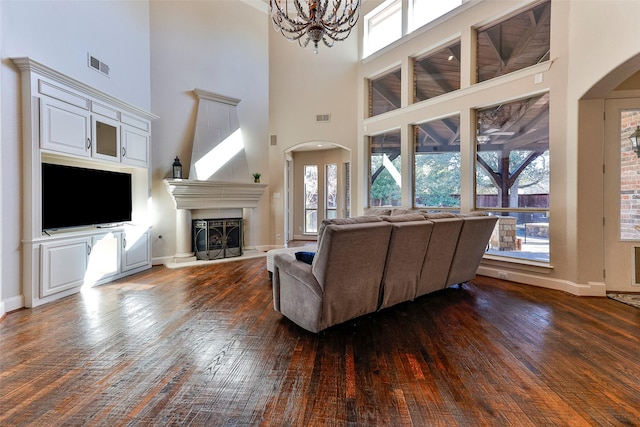 living room with dark wood-type flooring, a towering ceiling, and a notable chandelier