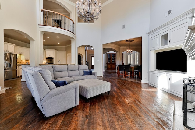 living room with a towering ceiling, dark hardwood / wood-style flooring, and a notable chandelier