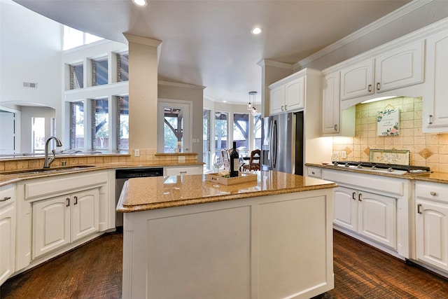 kitchen with white cabinetry, stainless steel appliances, light stone countertops, and a kitchen island