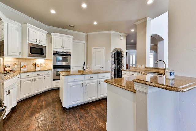 kitchen with sink, kitchen peninsula, white cabinets, and appliances with stainless steel finishes