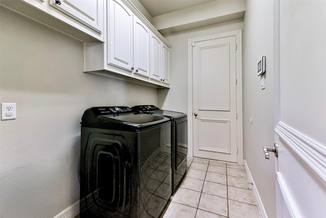 clothes washing area with cabinets, washing machine and dryer, and light tile patterned floors