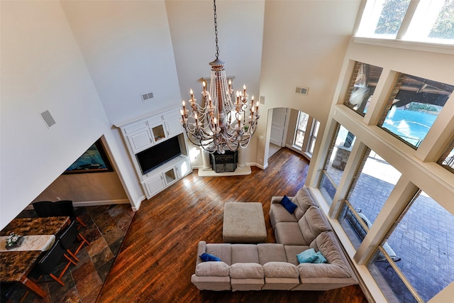 living room with an inviting chandelier, a towering ceiling, and dark hardwood / wood-style floors