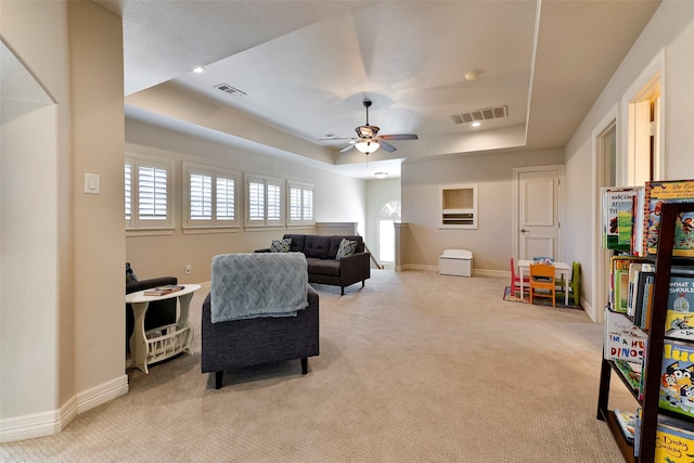 carpeted living room featuring ceiling fan and a tray ceiling