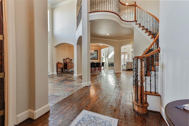 entrance foyer with crown molding, a towering ceiling, and dark hardwood / wood-style flooring