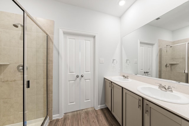 bathroom featuring wood-type flooring, an enclosed shower, and vanity