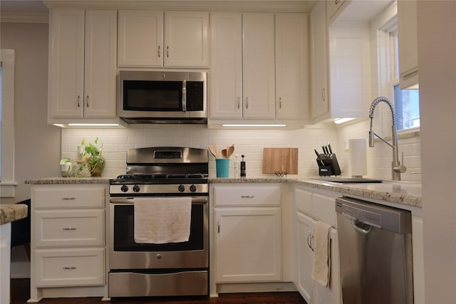 kitchen featuring stainless steel appliances, sink, white cabinetry, and light stone countertops