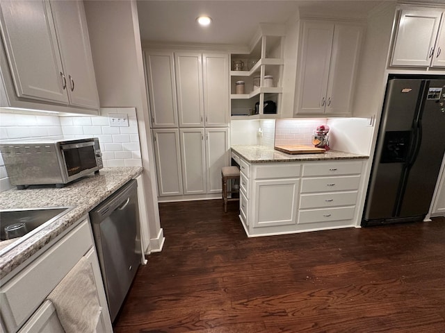 kitchen with light stone countertops, white cabinetry, appliances with stainless steel finishes, and dark hardwood / wood-style floors