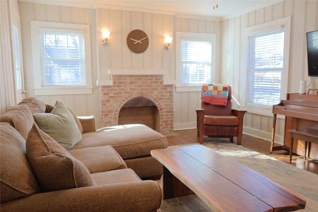 living room featuring a brick fireplace, hardwood / wood-style floors, and crown molding