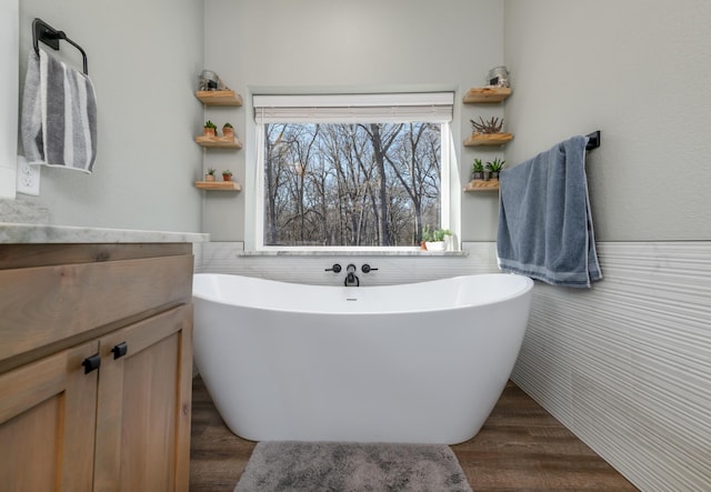 bathroom with tile walls, vanity, a bathtub, and wood-type flooring